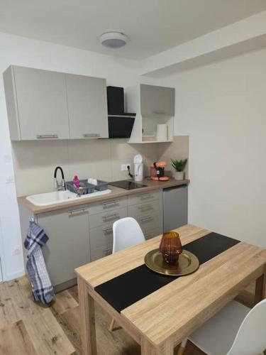 une cuisine avec une table en bois et des armoires blanches dans l'établissement 304 - Studio avec terrasse refait à neuf, à Strasbourg