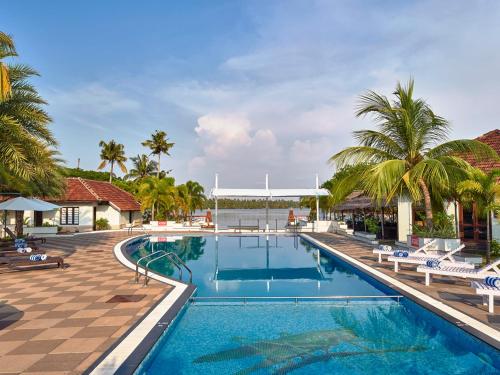 una piscina en un complejo con sillas y palmeras en Club Mahindra Cherai Beach, en Cherai Beach