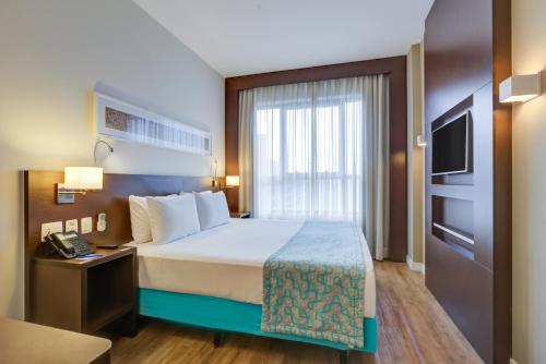 a hotel room with a bed and a television at Comfort Hotel São Caetano in São Caetano do Sul