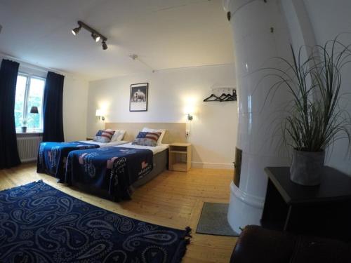 a bedroom with two beds and a potted plant at Hotell Östermalm in Motala