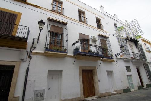 a white building with windows and balconies on a street at Apartamentos Centro Puerto de Santa Maria in El Puerto de Santa María