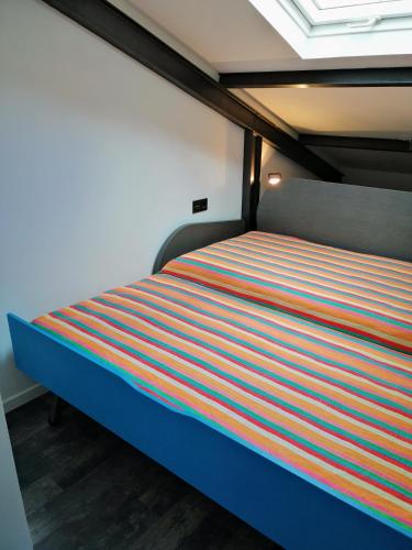 a bed with a colorful striped bedsheet in a room at VilafraggleRock, casa de diseño moderno en Pontedeume in Puentedeume
