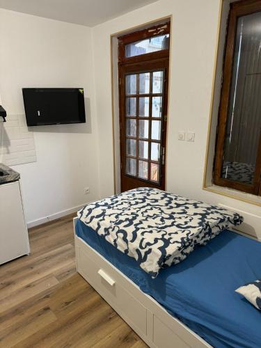 une chambre avec un lit et une télévision au mur dans l'établissement Proche de Kindarena à 10 min de Rouen, à Déville-lès-Rouen