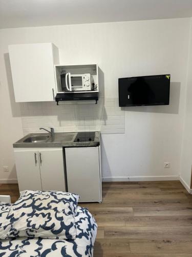 - une cuisine avec un évier et un four micro-ondes sur le mur dans l'établissement Proche de Kindarena à 10 min de Rouen, à Déville-lès-Rouen