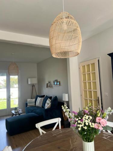 a living room with a blue couch and a table at Maison Cosy Bord de Mer in Dives-sur-Mer