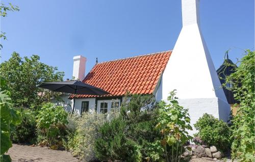 a white church with an umbrella in front of it at 2 Bedroom Awesome Home In Svaneke in Svaneke
