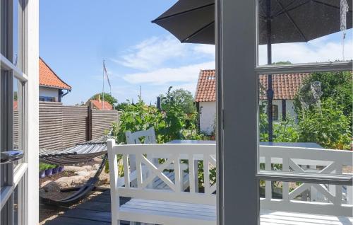 a porch with a white bench and an umbrella at 2 Bedroom Awesome Home In Svaneke in Svaneke