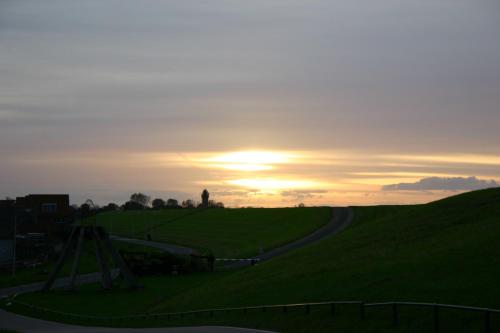 a sunset over a field with a winding road at Het Huis van de Wadden in Den Oever