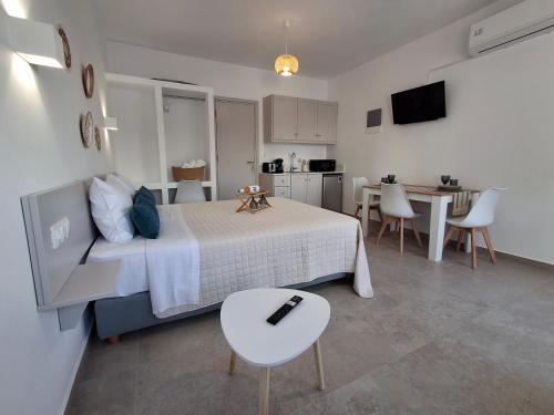 a bedroom with a bed and a table and a kitchen at Aegean Whisper in Masouri