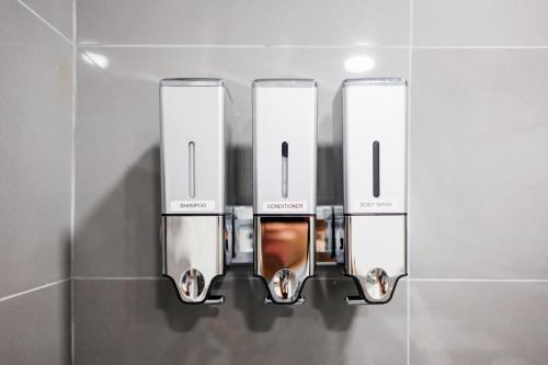 una fila de tres dispensadores de jabón en la pared del baño en Plumeria Housing, en Fort Lauderdale