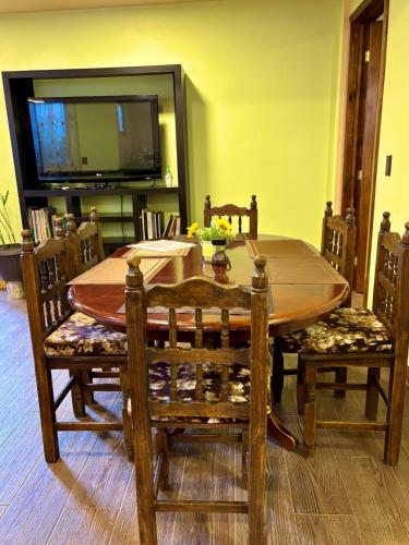 a wooden dining room table with chairs and a television at SiempreViva Hospedaje By GEstores in Chignahuapan