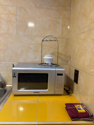a microwave sitting on top of a yellow counter at SiempreViva Hospedaje By GEstores in Chignahuapan