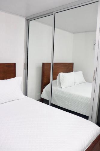 two beds in a room with a mirror at Airport SJO Residence - Edward & Familia Inn in Alajuela City