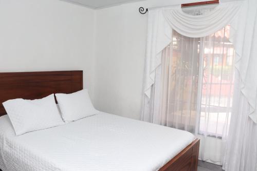 a bedroom with a white bed and a window at Airport SJO Residence - Edward & Familia Inn in Alajuela City