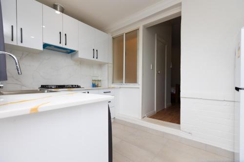 a white kitchen with white cabinets and a sink at Glenelg North Modern Studio, QBed,Wifi, Pet in Glenelg