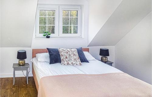 a bedroom with a bed with two night stands and two windows at Amazing Home In Silec With Sauna in Srokowo