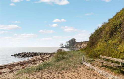 a bench sitting on a beach next to the water at Nice Home In Juelsminde With Kitchen in Juelsminde