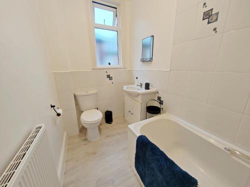 a white bathroom with a tub and a toilet at Central Manchester Modern 4 Bed House - free parking in Manchester