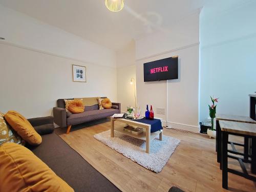 a living room with a couch and a tv on the wall at Central Manchester Modern 4 Bed House - free parking in Manchester
