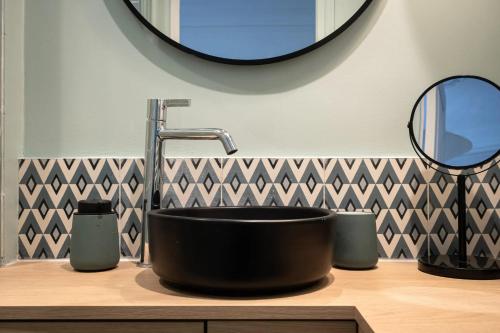 une salle de bain avec un lavabo noir et un miroir dans l'établissement Appartement charmant à Paris 31 m² avec équipements modernes, à Paris
