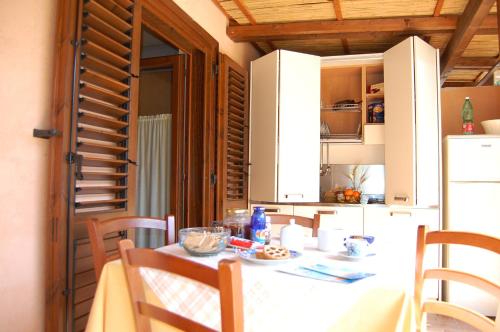 a kitchen with a table and a white refrigerator at Family Resort Cala di Luna in Marina di Camerota