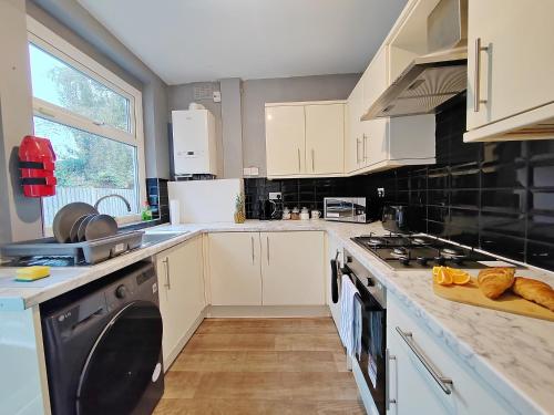 a kitchen with white cabinets and black appliances at Central Manchester Modern 4 Bed House - free parking in Manchester