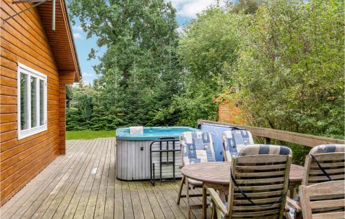 a deck with a table and chairs and a hot tub at Awesome Home In Fårvang With Sauna in Fårvang