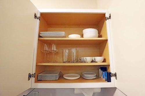 a cupboard filled with plates and bowls and dishes at South of Fifth Studio Steps to Beach on Ocean Drive in Miami Beach