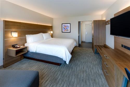 a hotel room with a bed and a flat screen tv at Holiday Inn Express & Suites - Middletown - Goshen by IHG in Middletown