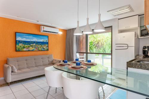 a kitchen and living room with a glass table at Flat ou Bangalo Luxo Beach Class Beira Mar Muro Alto in Porto De Galinhas