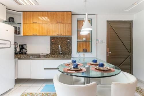 a kitchen with a glass table and white chairs at Flat ou Bangalo Luxo Beach Class Beira Mar Muro Alto in Porto De Galinhas