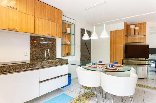 a kitchen with a glass table and white cabinets at Flat ou Bangalo Luxo Beach Class Beira Mar Muro Alto in Porto De Galinhas