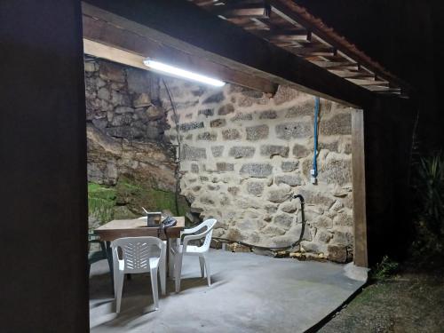 a patio with a table and chairs and a stone wall at Casinha Ponte Nova in Monção