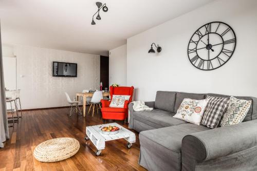a living room with a couch and a clock on the wall at Glob Apartament Sea Towers Gdynia in Gdynia