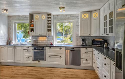 a large white kitchen with white cabinets and windows at Nice Home In Norra Kedum With Wifi in Norra Kedum