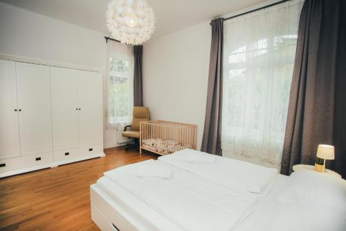 a bedroom with two white beds and a chandelier at Little Swiss in Sigulda