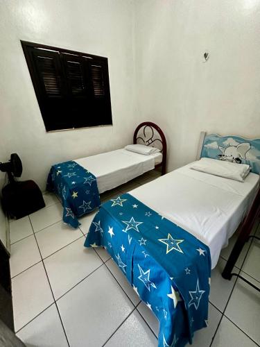 two beds in a room with stars on the sheets at Casinha da vovó in Tutóia