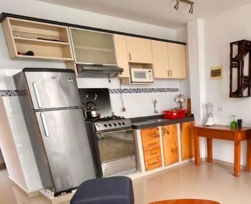 a kitchen with a stainless steel refrigerator and wooden cabinets at Departamento COCO - San Bartolo in San Bartolo