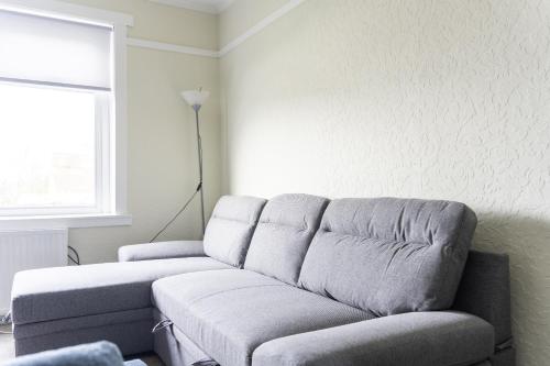 a living room with a couch and a window at Raploch House in Larkhall