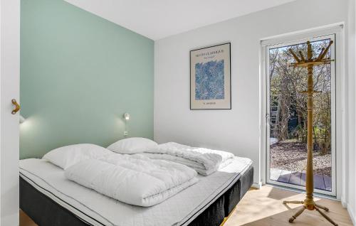 a bedroom with a bed with white sheets and a window at Beautiful Home In Sjællands Odde in Yderby