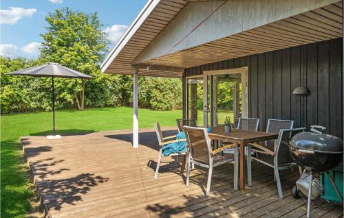 a wooden deck with a grill and a table and chairs at 3 Bedroom Amazing Home In Børkop in Børkop