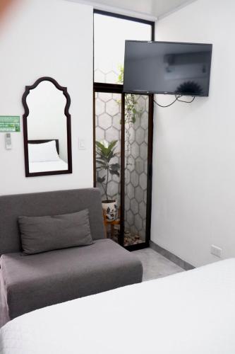 a bedroom with a bed and a couch and a mirror at Airport SJO Residence - Edward & Familia Inn in Alajuela City