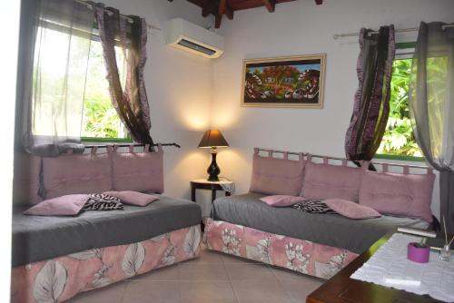 a room with two beds and a table and windows at Gite d'arles Bungalow "La Rose" in Le Moule