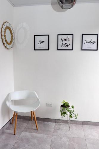 a white chair in a room with four pictures on the wall at Airport SJO Residence - Edward & Familia Inn in Alajuela City