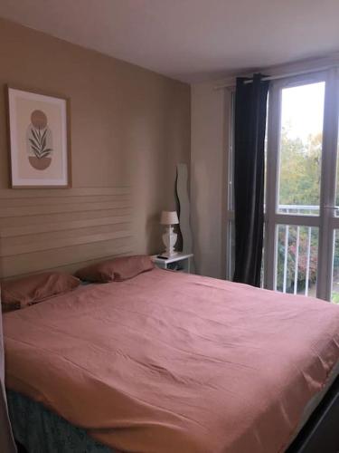 - une chambre avec un grand lit rose et une fenêtre dans l'établissement Escapade à 15 mn de L'aéroport Orly 20mn de paris, à Chilly-Mazarin