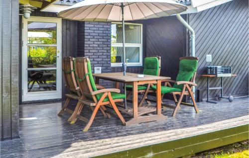 a table and chairs on a porch with an umbrella at Nice Home In Glesborg With Kitchen in Bønnerup Strand