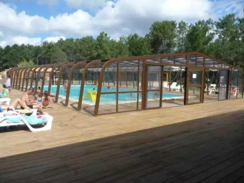 - un pavillon avec une piscine et des personnes assises à côté dans l'établissement Camping 4 étoiles - Piscine - eebe0d, à Saint-Michel-Escalus