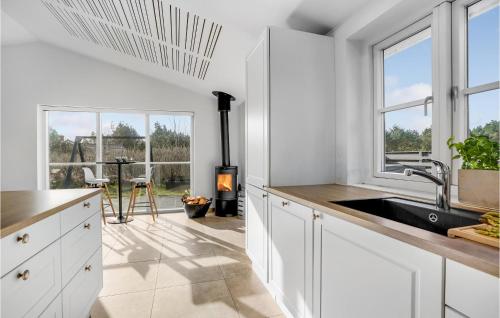a kitchen with white cabinets and a stove at Awesome Home In Blåvand With Sauna in Blåvand