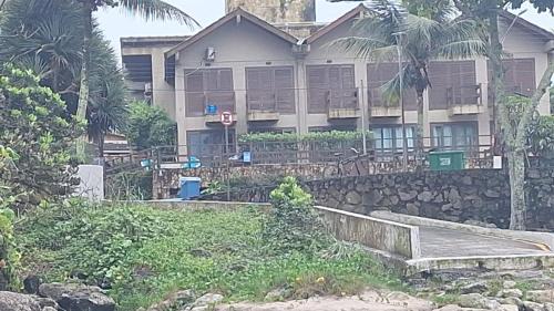 a house with a stone wall in front of it at Quarto lateral da beira mar - tombo - guarujá in Guarujá