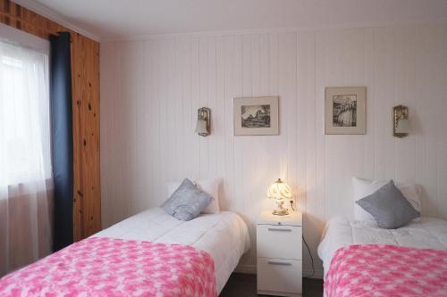 a bedroom with two beds and a table with a lamp at Auberge St-Tite-des-Caps in Saint-Tite-des-Caps